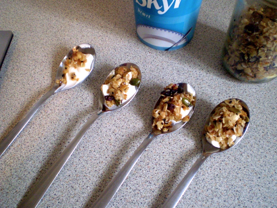 four spoons are laid out, each with a different proportion of granola to skyr.
